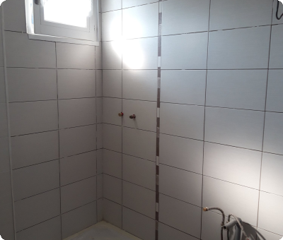 Douche italienne en cours, carrelage posé, tuyaux visibles