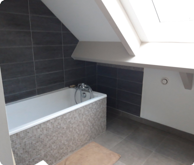 Salle de bain finalisée avec baignoire et carrelage moderne, sous combles