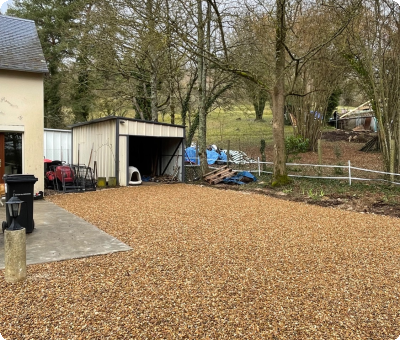Cour en gravillons terminée avec abri et arbres autour
