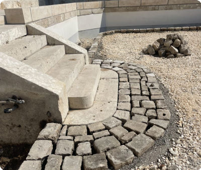 Restauration de pavés en cours autour d'un escalier en béton