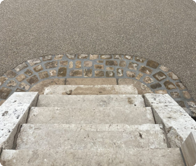Escalier en pierre menant à une place en béton restaurée après travaux