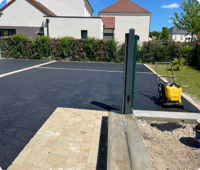 Cour aménagée en enrobé noir avec place en béton désactivé après travaux